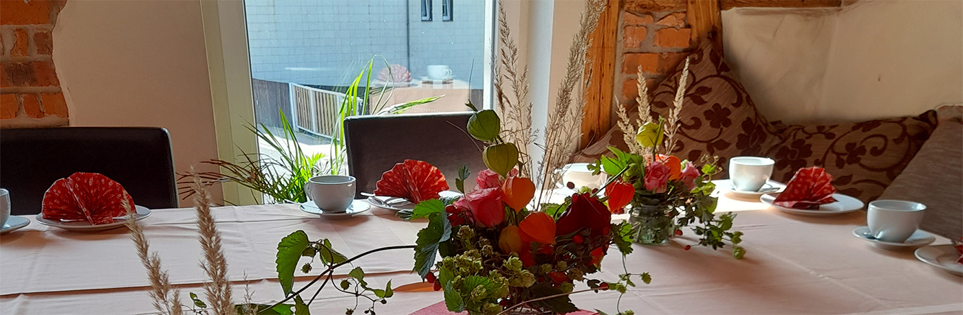 Tisch am Fenster, auf dem Tisch Teetassen und Blumensträuße